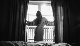 Zimmer im 4-Sterne Superior Boutique Hotel am Wolfgangsee Frau steht am Fenster im Zimmer des 4-Sterne Boutique Hotels Cortisen am Wolfgangsee