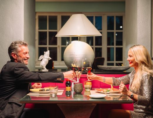 Gourmet Restaurant im Boutique Hotel Cortisen am Wolfgangsee Paar stößt mit Wein im Boutique Hotel Cortisen am Wolfgangsee an
